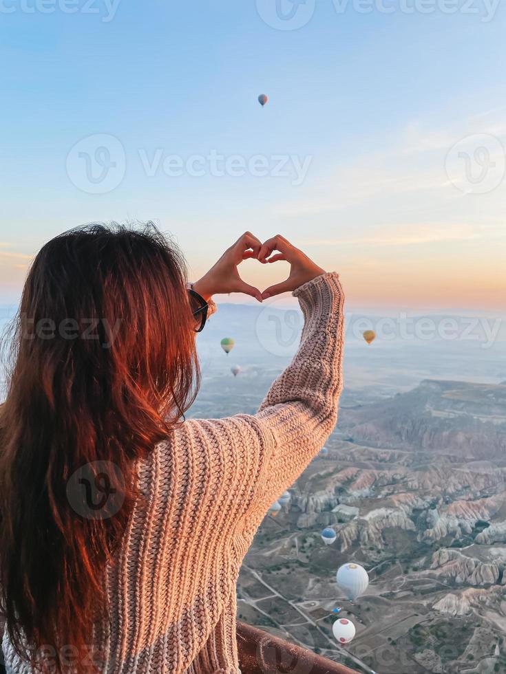 mulher feliz durante o nascer do sol assistindo balões de ar quente na capadócia, turquia foto