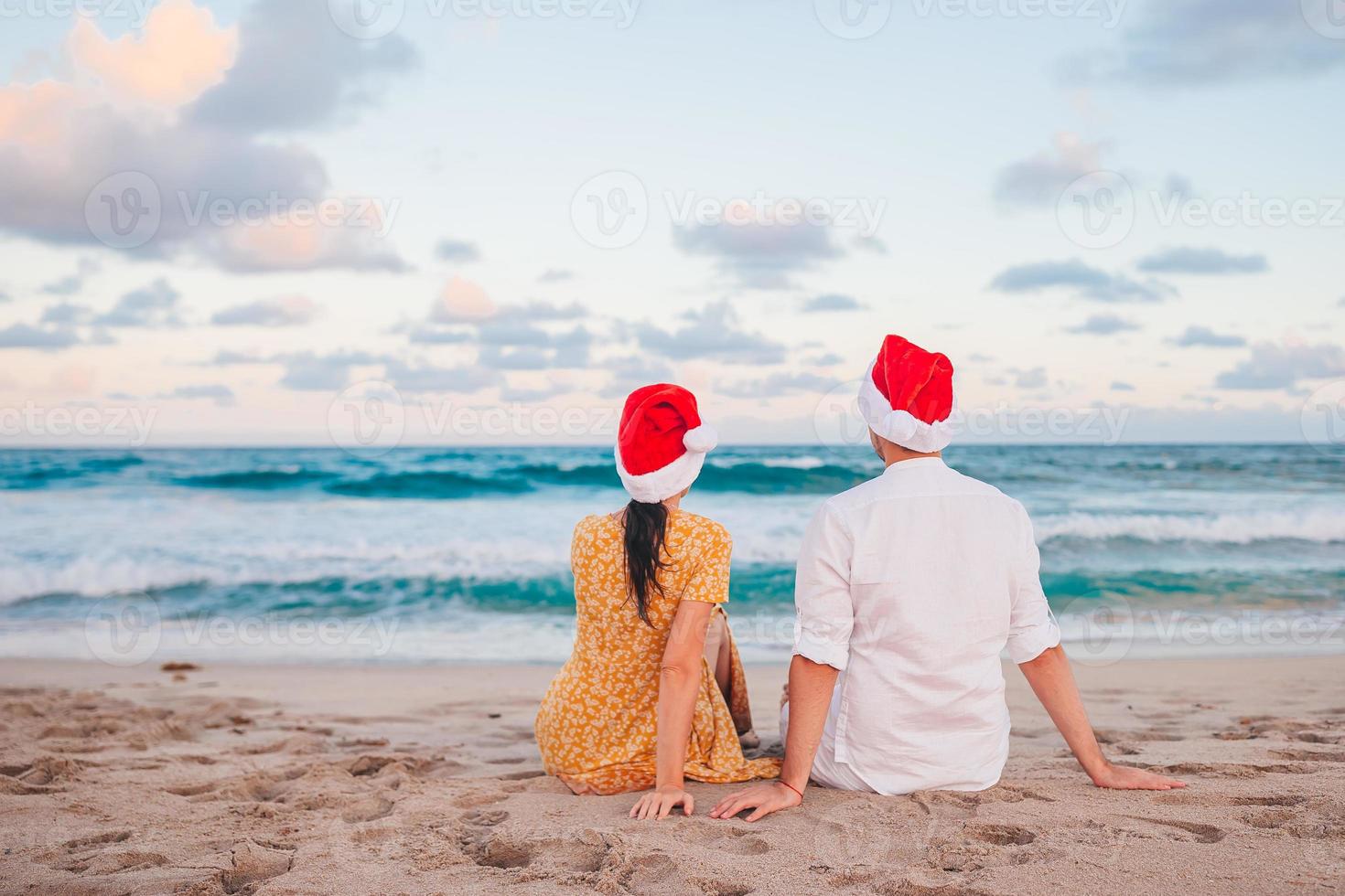 casal feliz em chapéus de papai noel nas férias de praia de natal foto