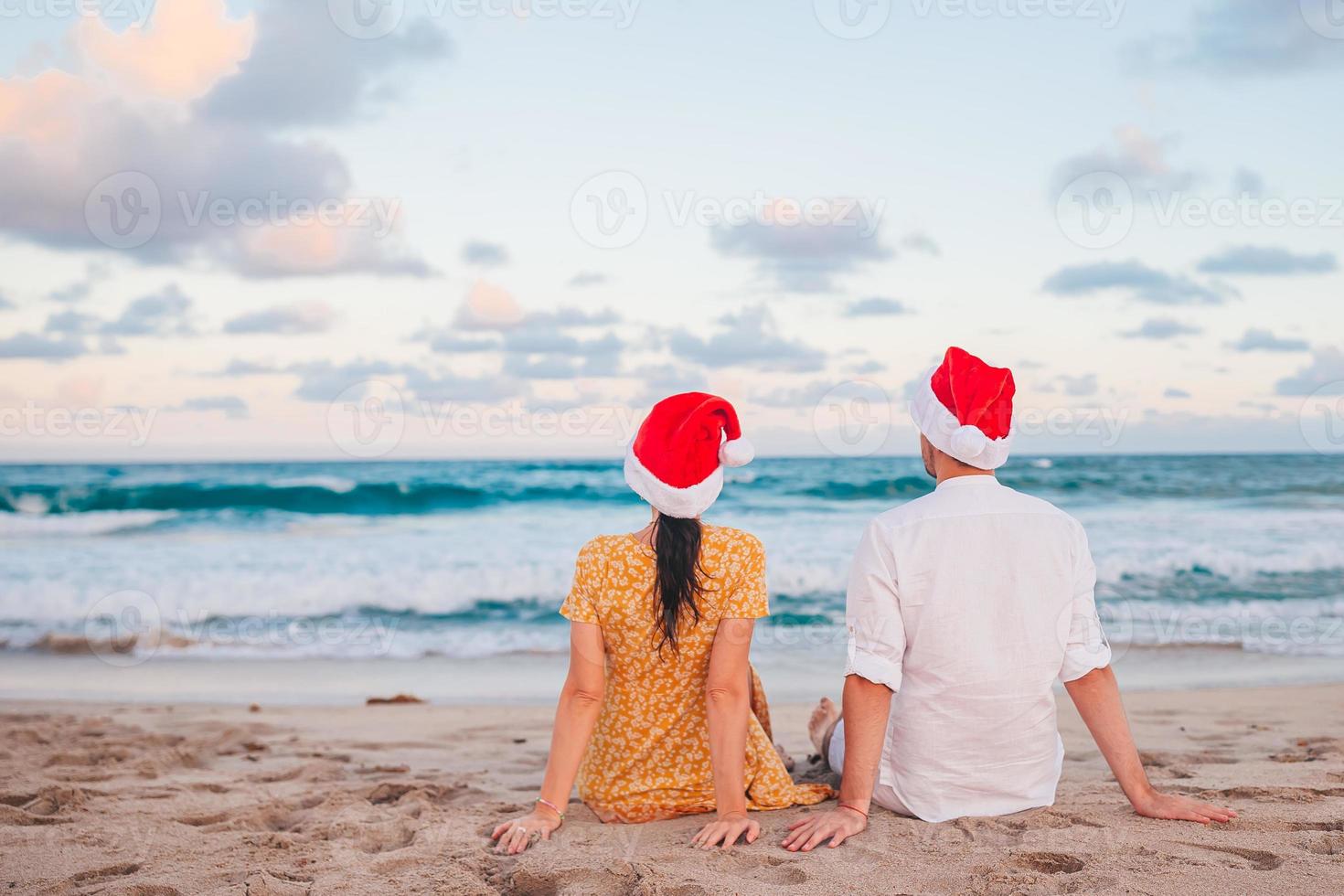 casal feliz de natal em chapéus de papai noel nas férias na praia foto