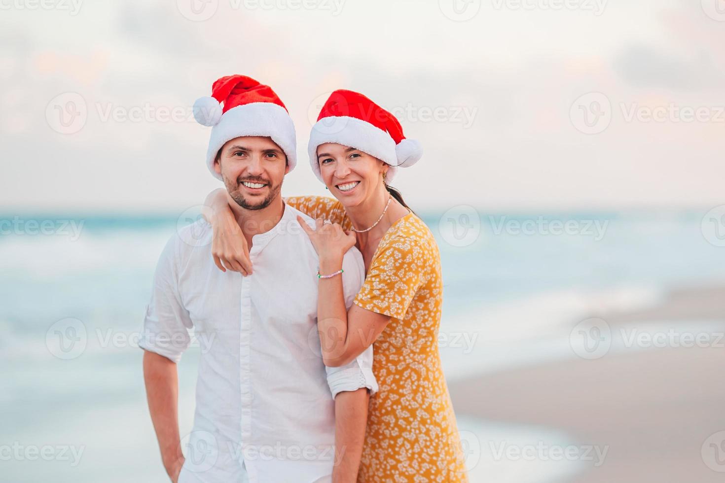 casal feliz de natal em chapéus de papai noel nas férias na praia foto