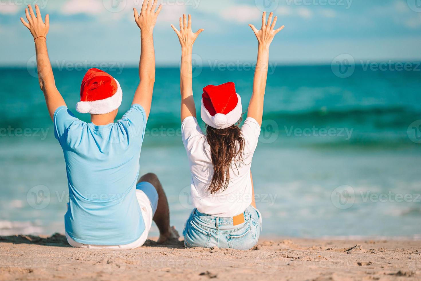 casal feliz de natal em chapéus de papai noel nas férias na praia foto