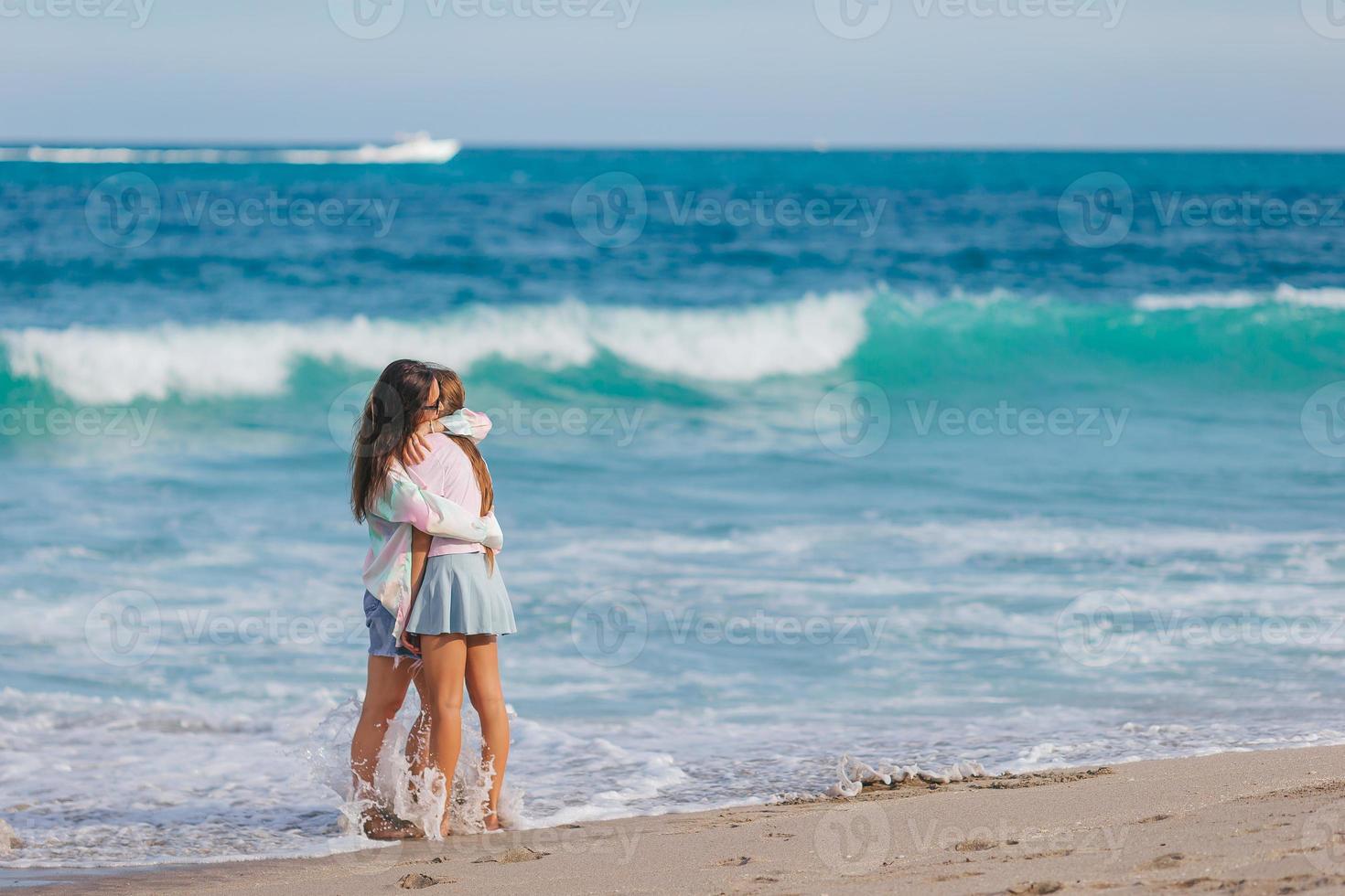 adorável menina e jovem mãe na praia tropical branca foto