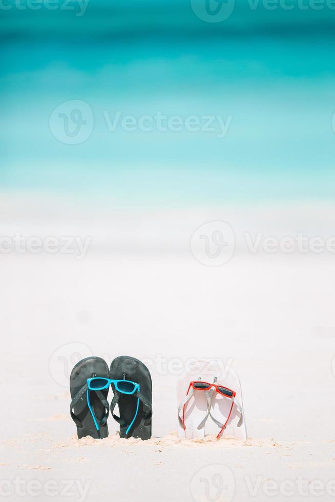 chinelos de verão com óculos de sol na praia branca. acessórios de praia closeup. foto