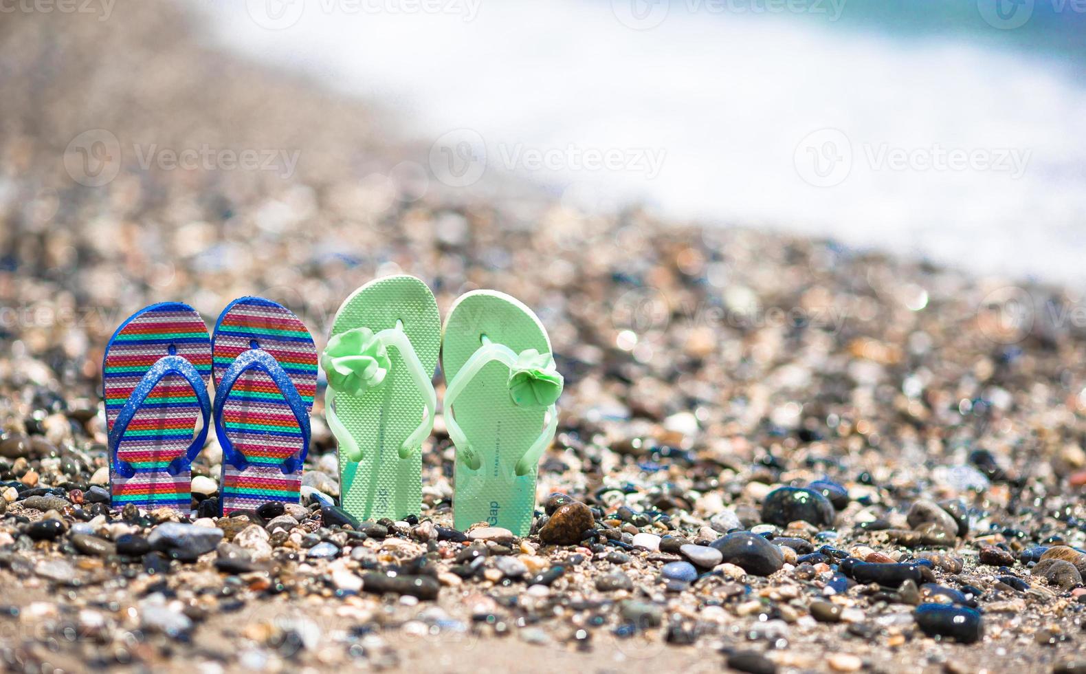 chinelos coloridos para crianças na praia em frente ao mar mediterrâneo foto