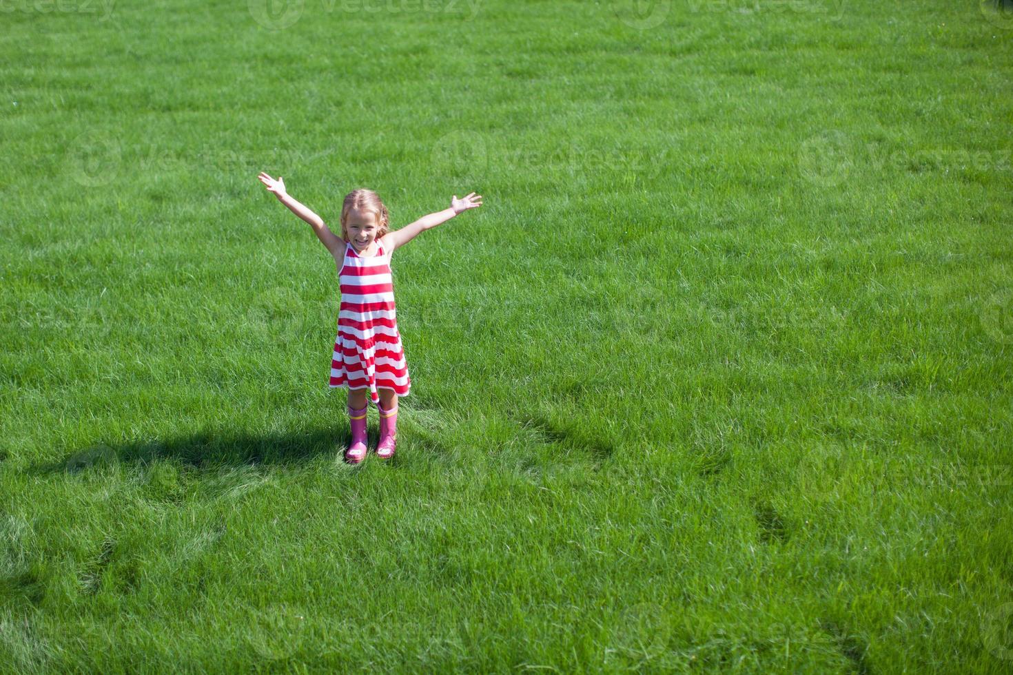 linda garotinha abriu os braços em pé no gramado foto