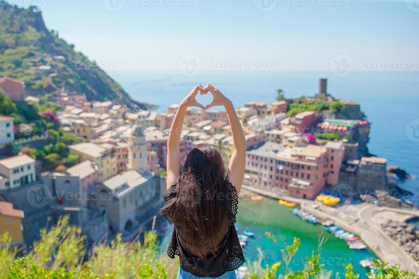 linda garota fazendo com as mãos em forma de coração no antigo fundo da cidade costeira de vernazza, parque nacional de cinque terre, ligúria, itália, europa foto