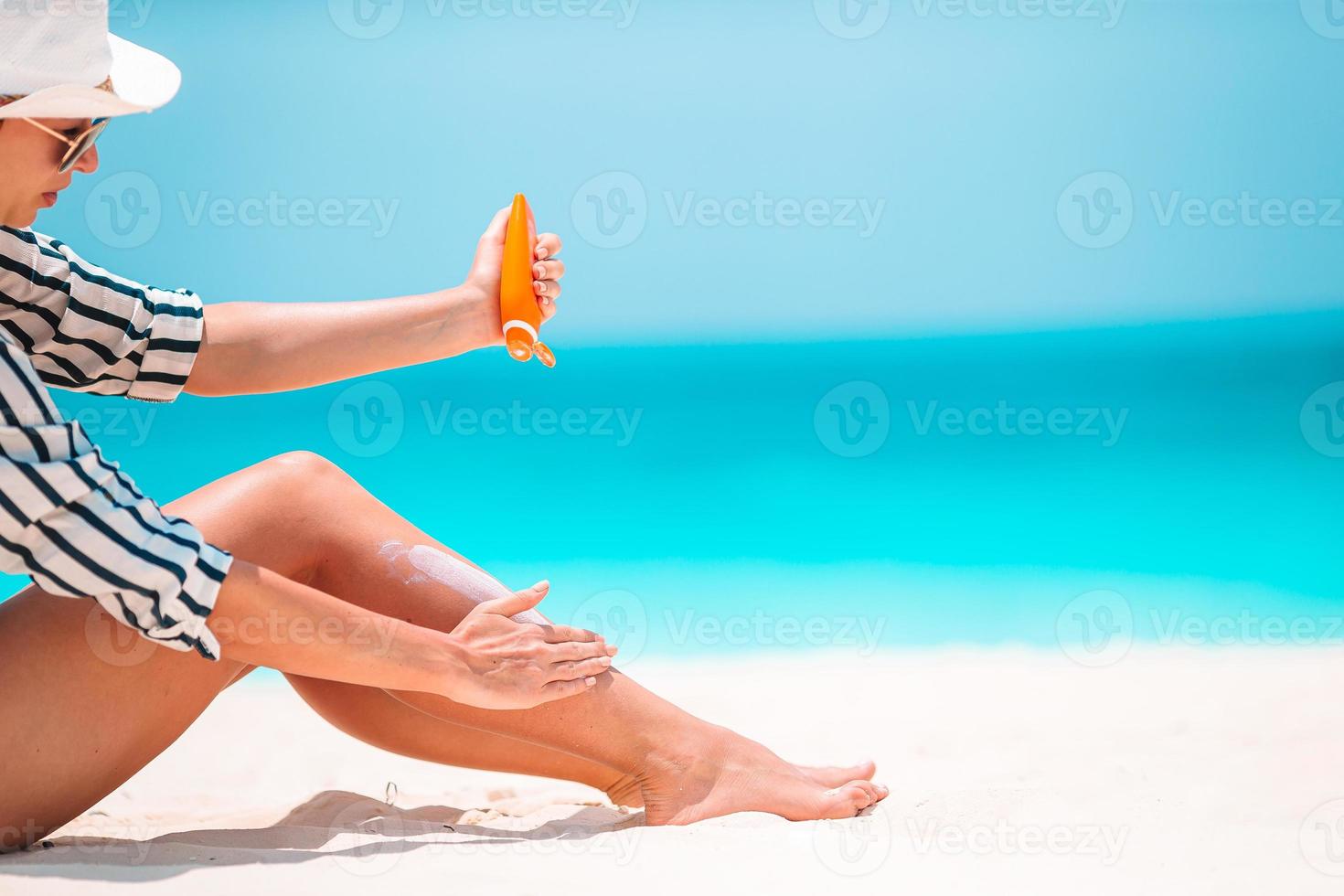 jovem aplicando protetor solar na praia branca foto