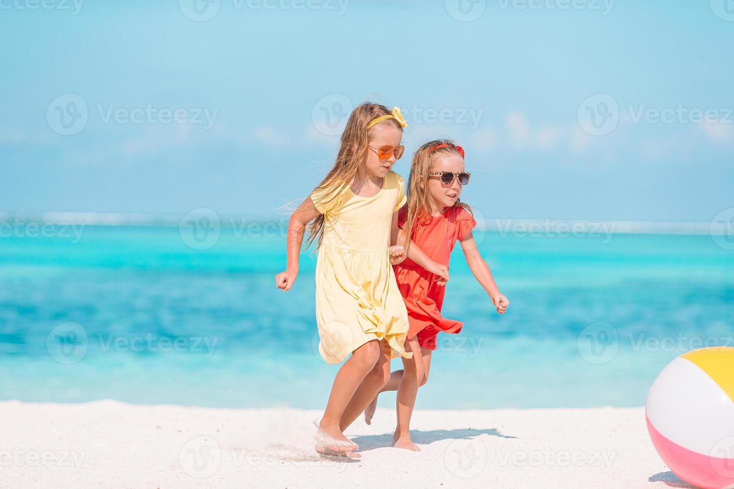 adoráveis meninas brincando com bola de ar na praia. crianças se divertindo à beira-mar foto