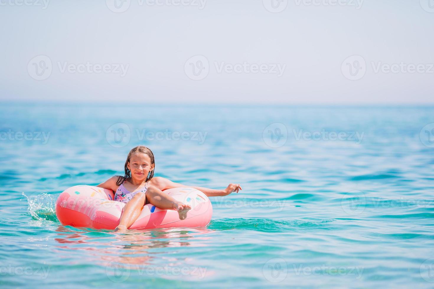 menina adorável no colchão de ar inflável no mar foto