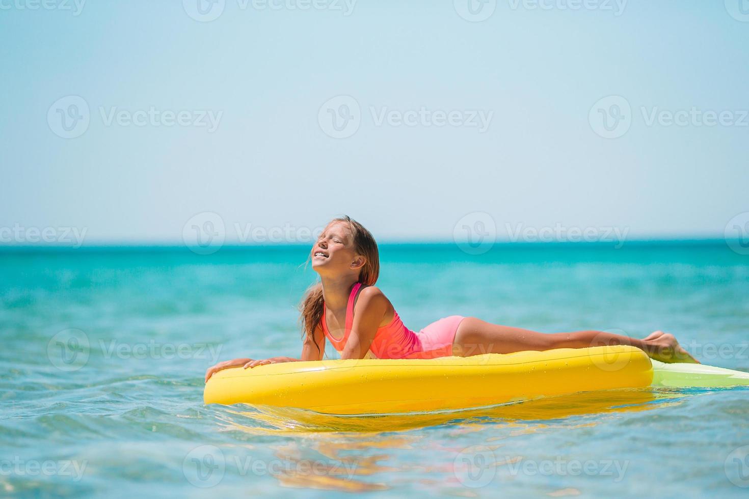 menina adorável no colchão de ar inflável no mar foto