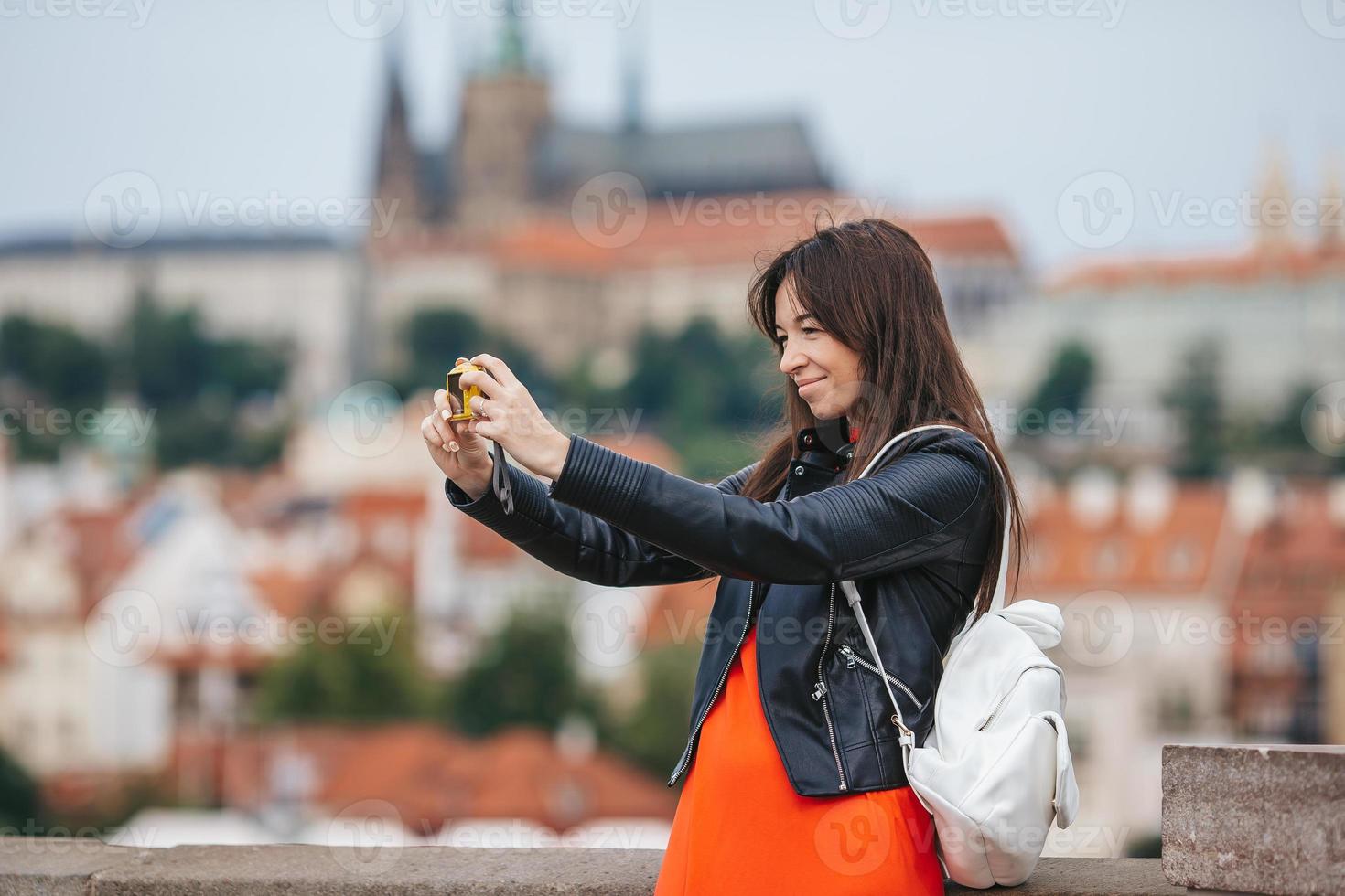 jovem mulher tomando selfie em smartphone na ponte charles em praga, foto