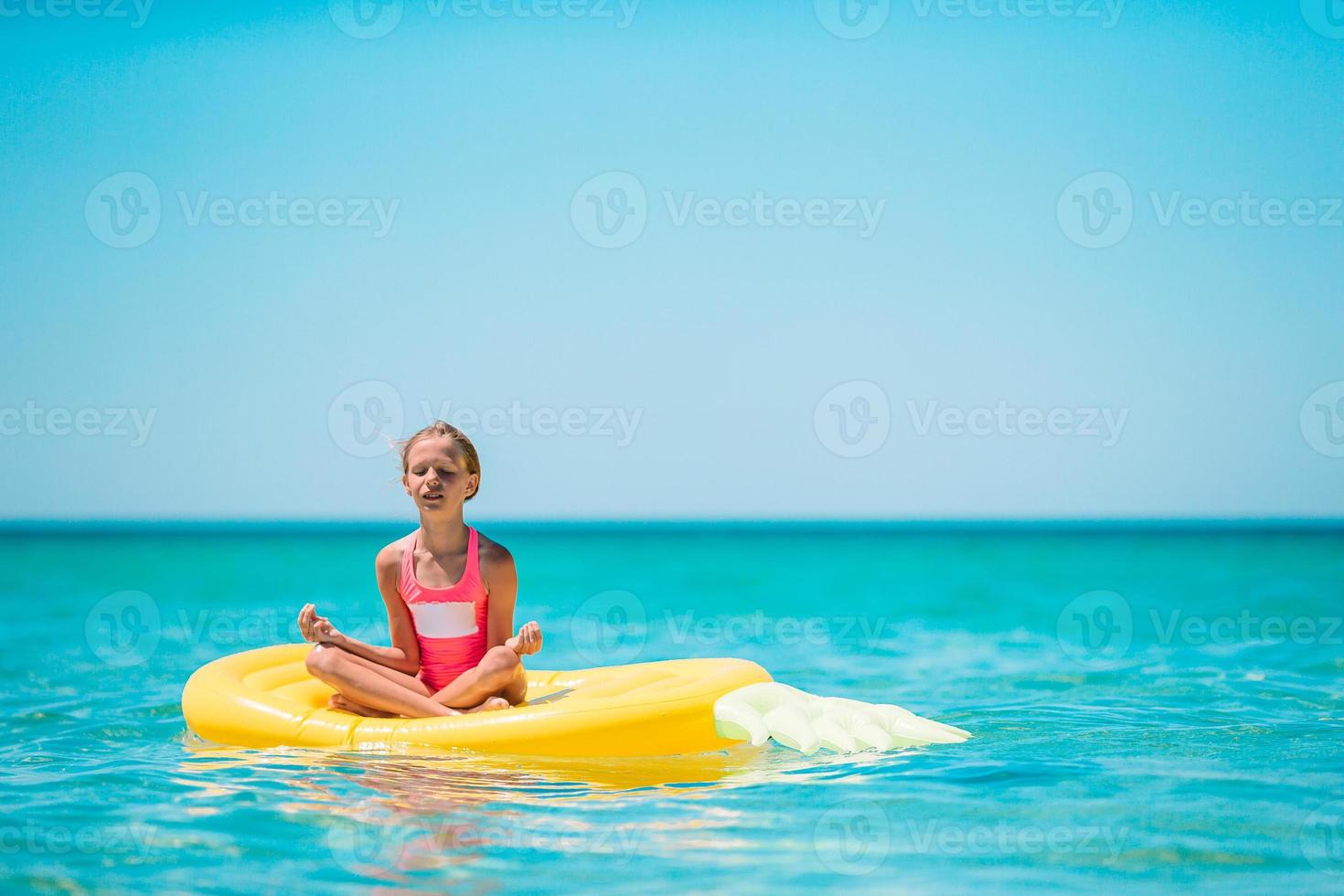 menina adorável no colchão de ar inflável no mar foto