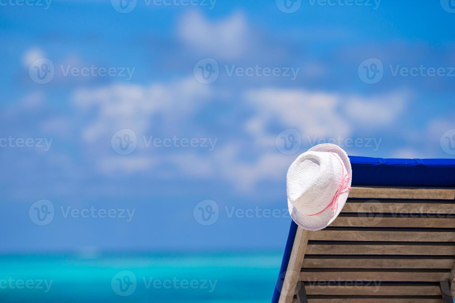 espreguiçadeiras com chapéu na praia branca tropical foto