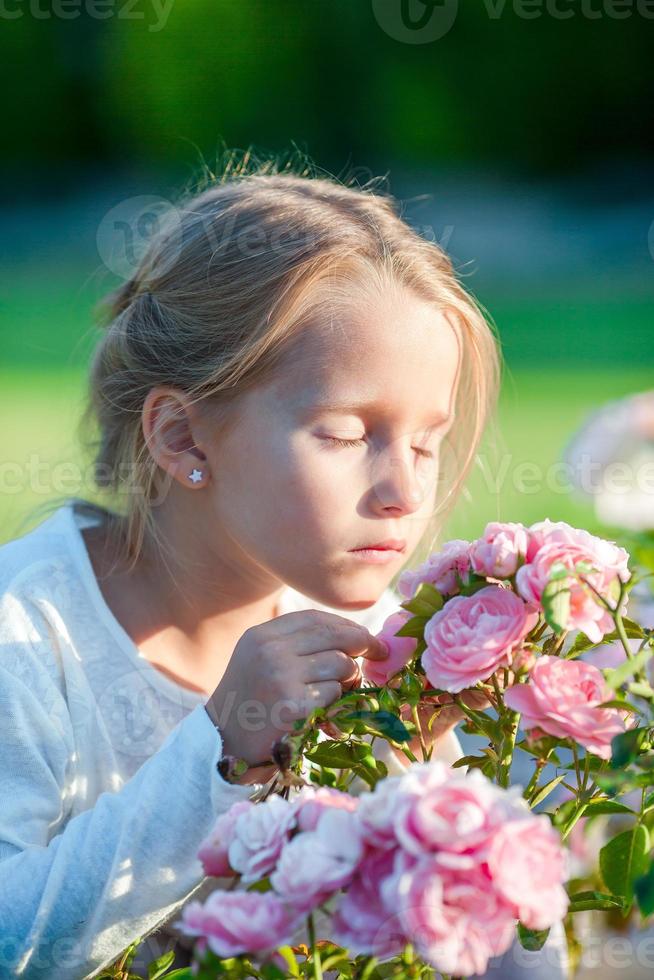 menina adorável cheirando flores coloridas ao ar livre foto