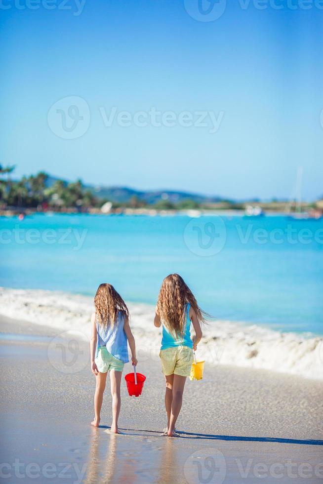 adoráveis meninas brincando com areia na praia. vista traseira de crianças caminhando na praia foto