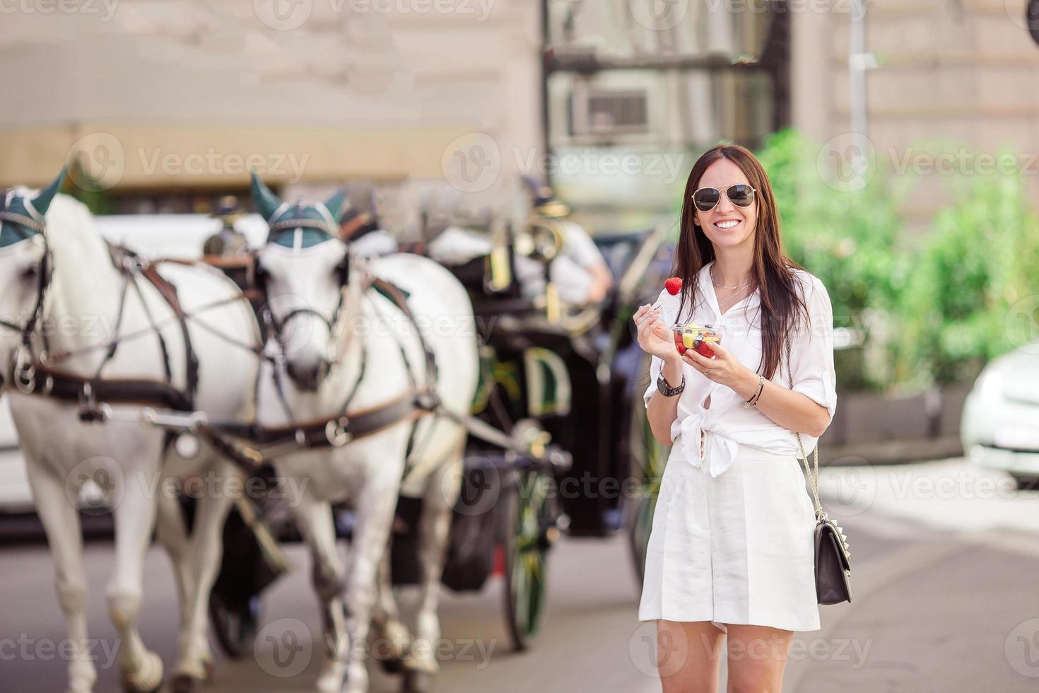 menina turista aproveitando as férias em viena e olhando para os belos cavalos na carruagem foto