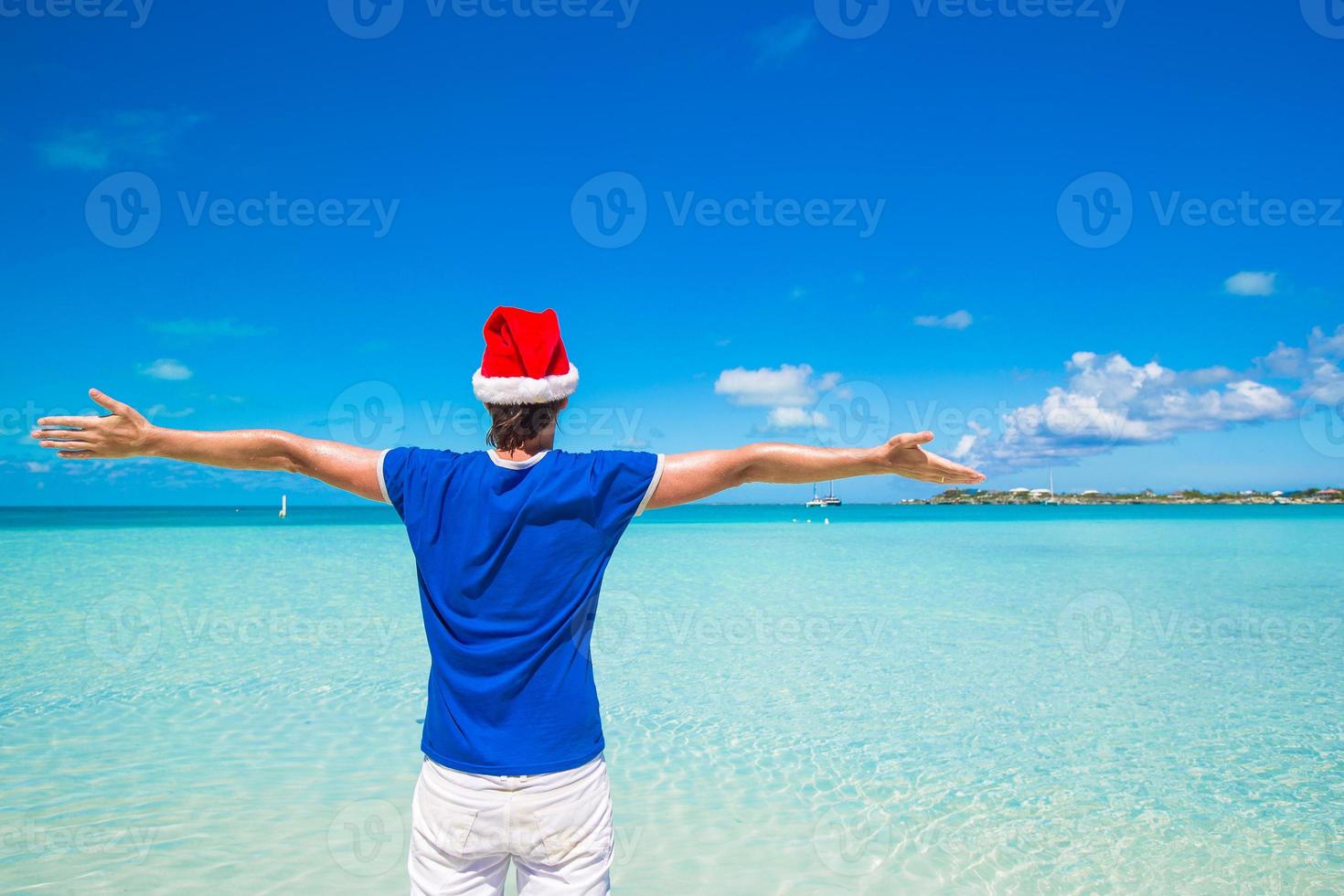 jovem de chapéu de Papai Noel na praia tropical foto