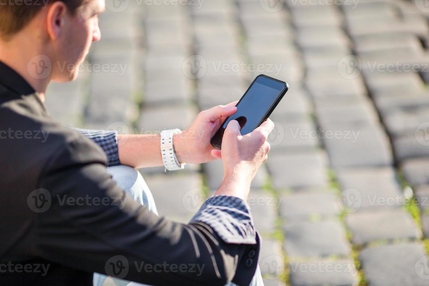 closeup de mãos masculinas está segurando o celular ao ar livre na rua. homem usando smartphone móvel. foto