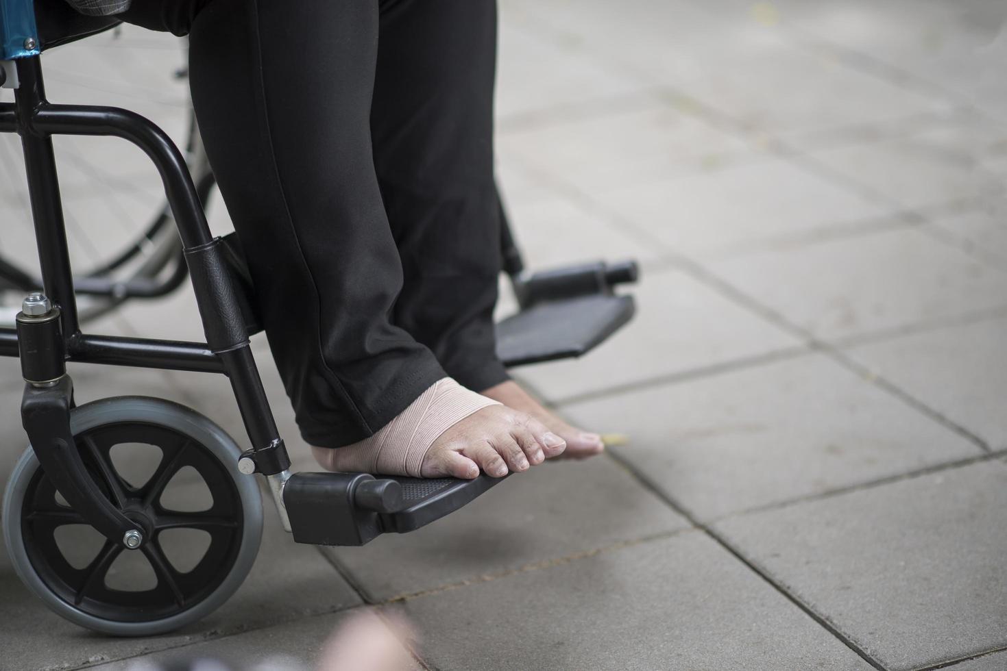 close-up de uma pessoa idosa em uma cadeira de rodas com dor no pé foto