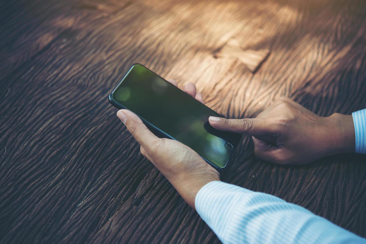 pessoa segurando um telefone inteligente em uma mesa foto