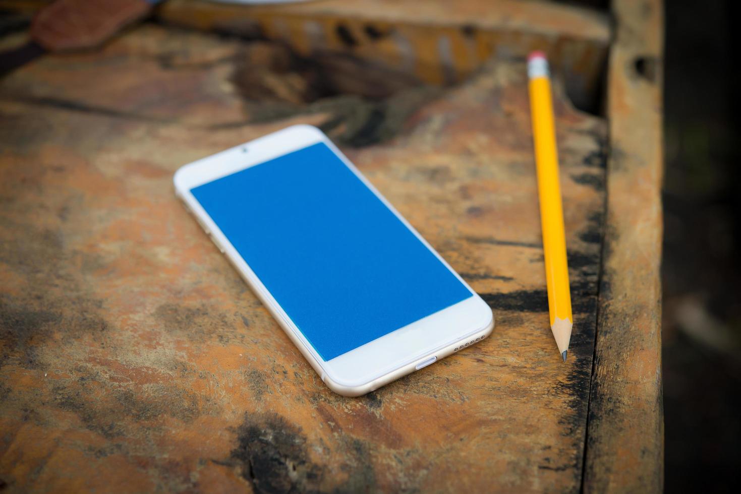 smartphone com lápis em uma mesa de madeira foto