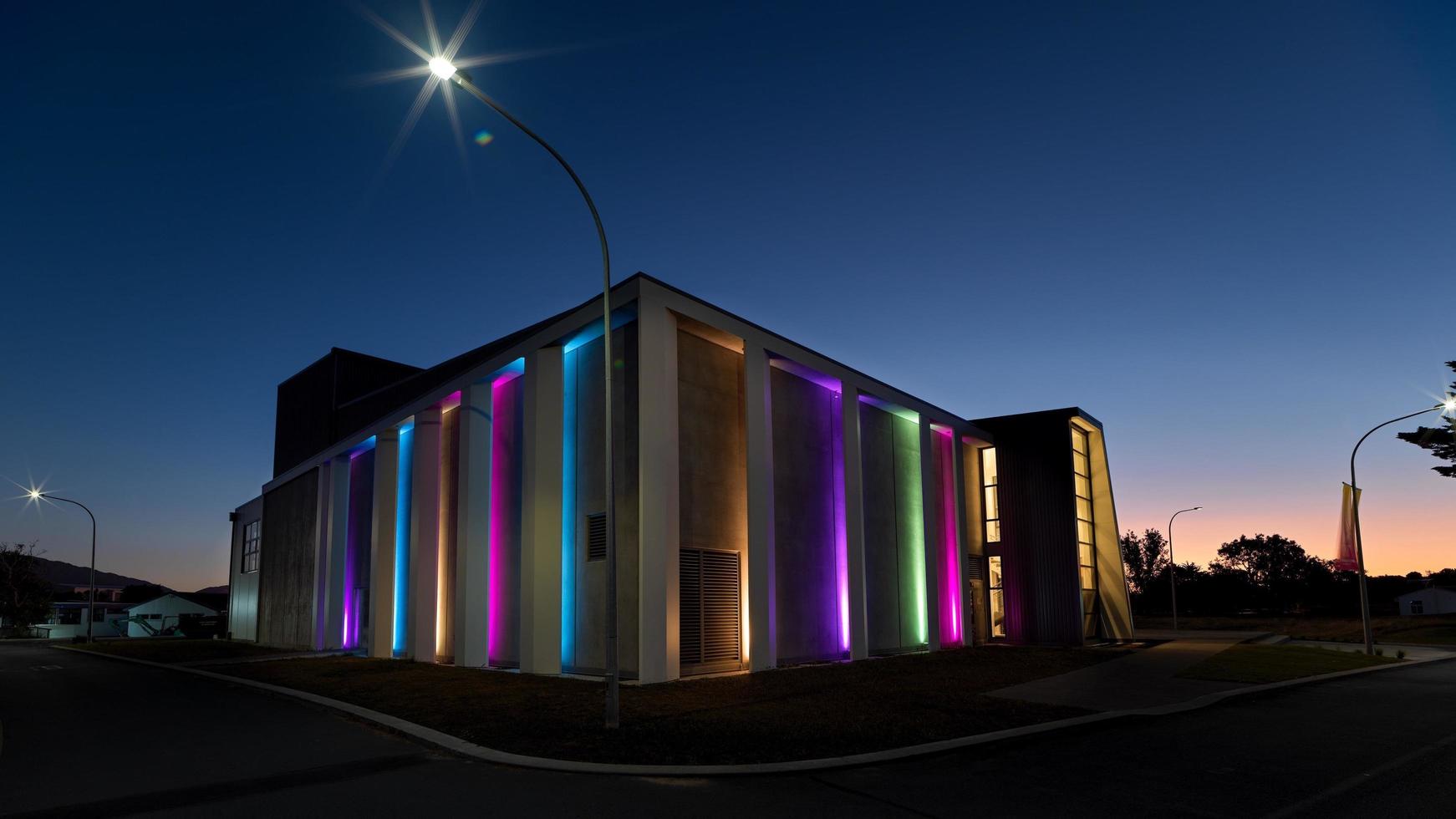 edifício iluminado de verde roxo e amarelo durante a noite foto