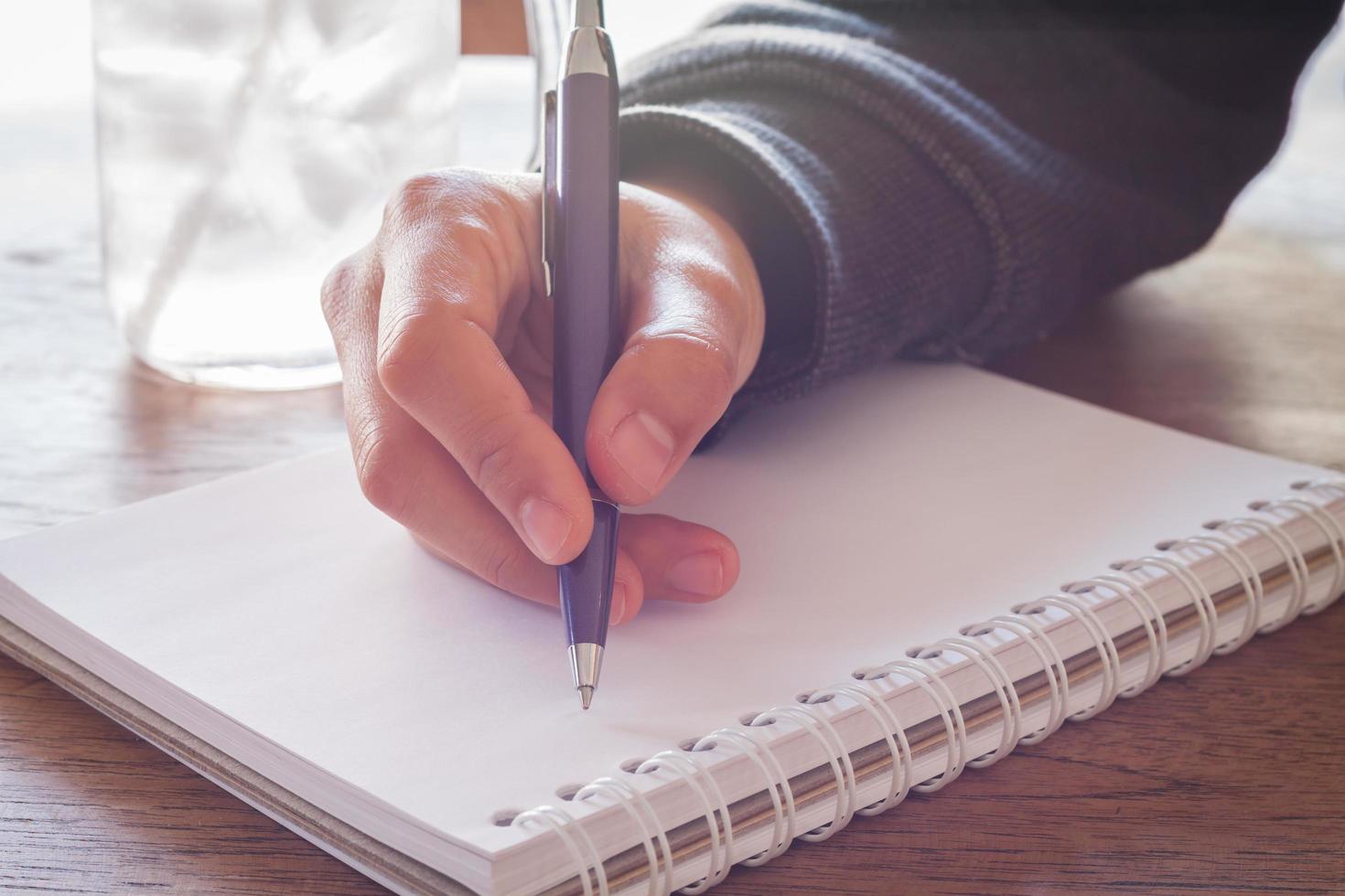 mão escrevendo com uma caneta roxa foto