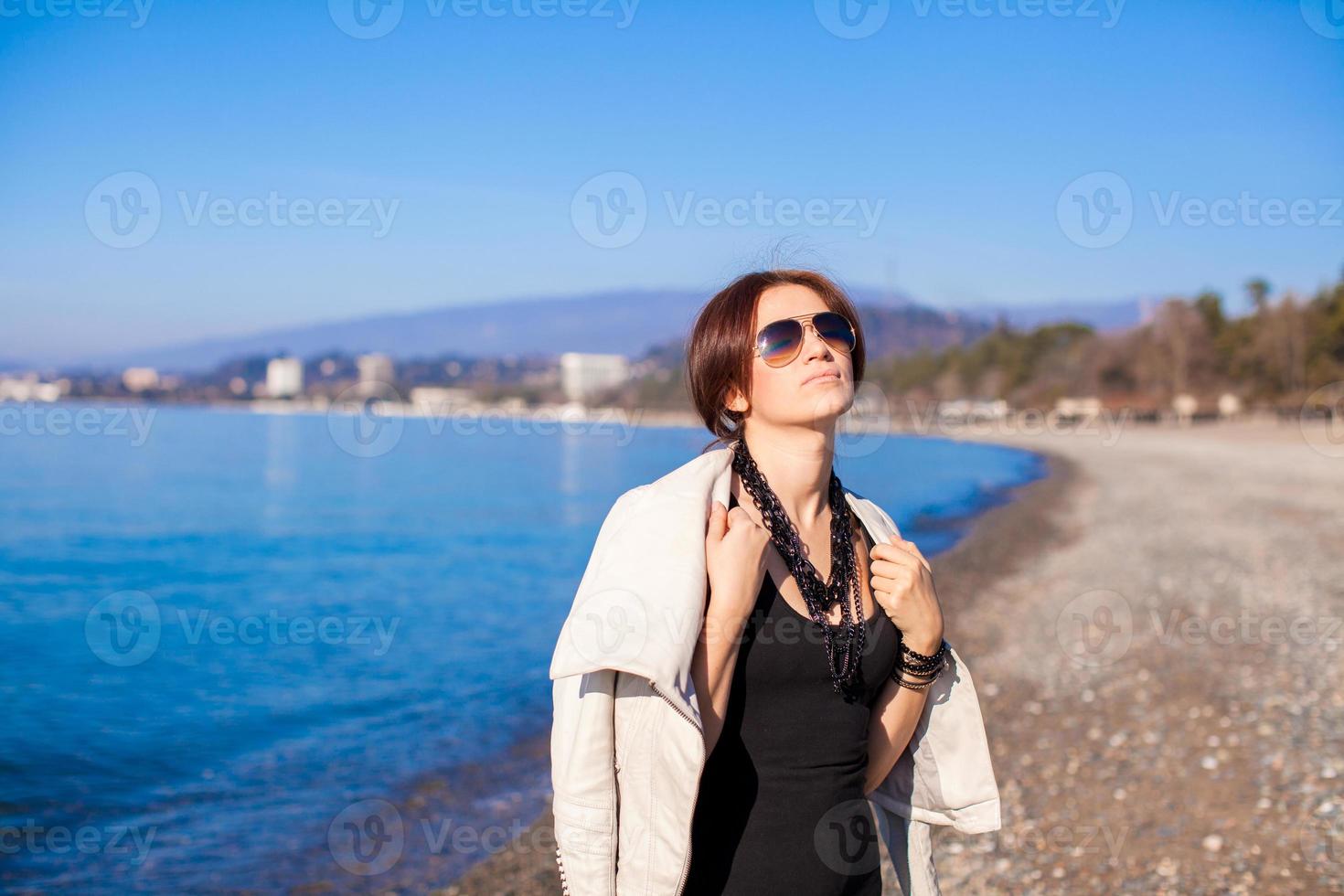 bela jovem relaxar na praia em um dia ensolarado de inverno sozinha foto