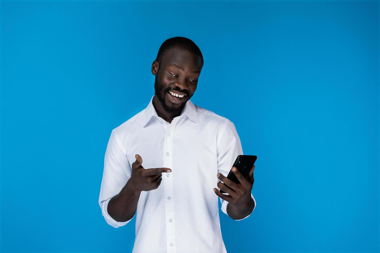 um homem sorridente olhando para o telefone foto