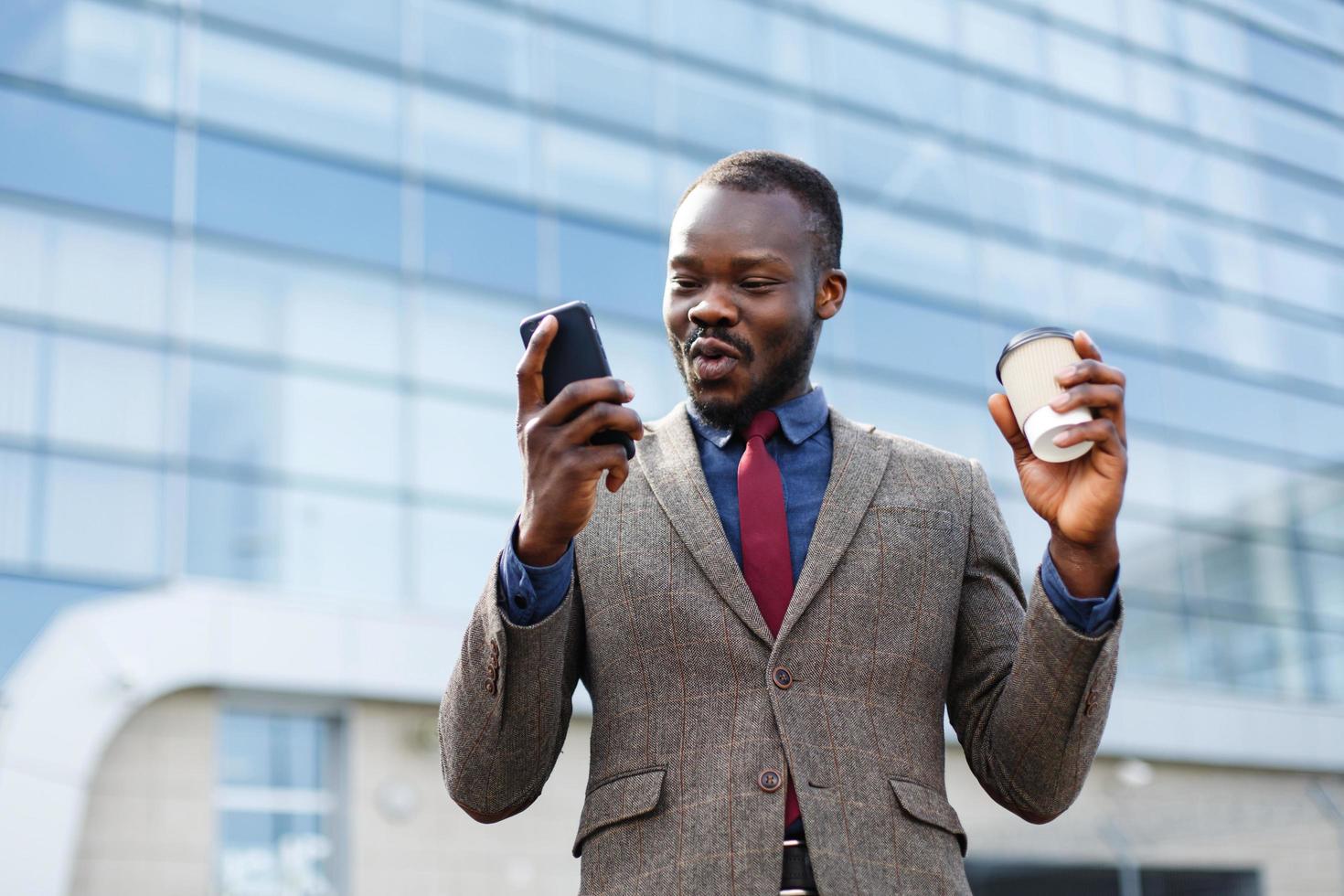 homem com um café lendo em seu telefone foto