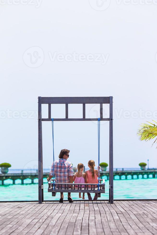 pai feliz e suas adoráveis filhas na praia tropical se divertindo foto
