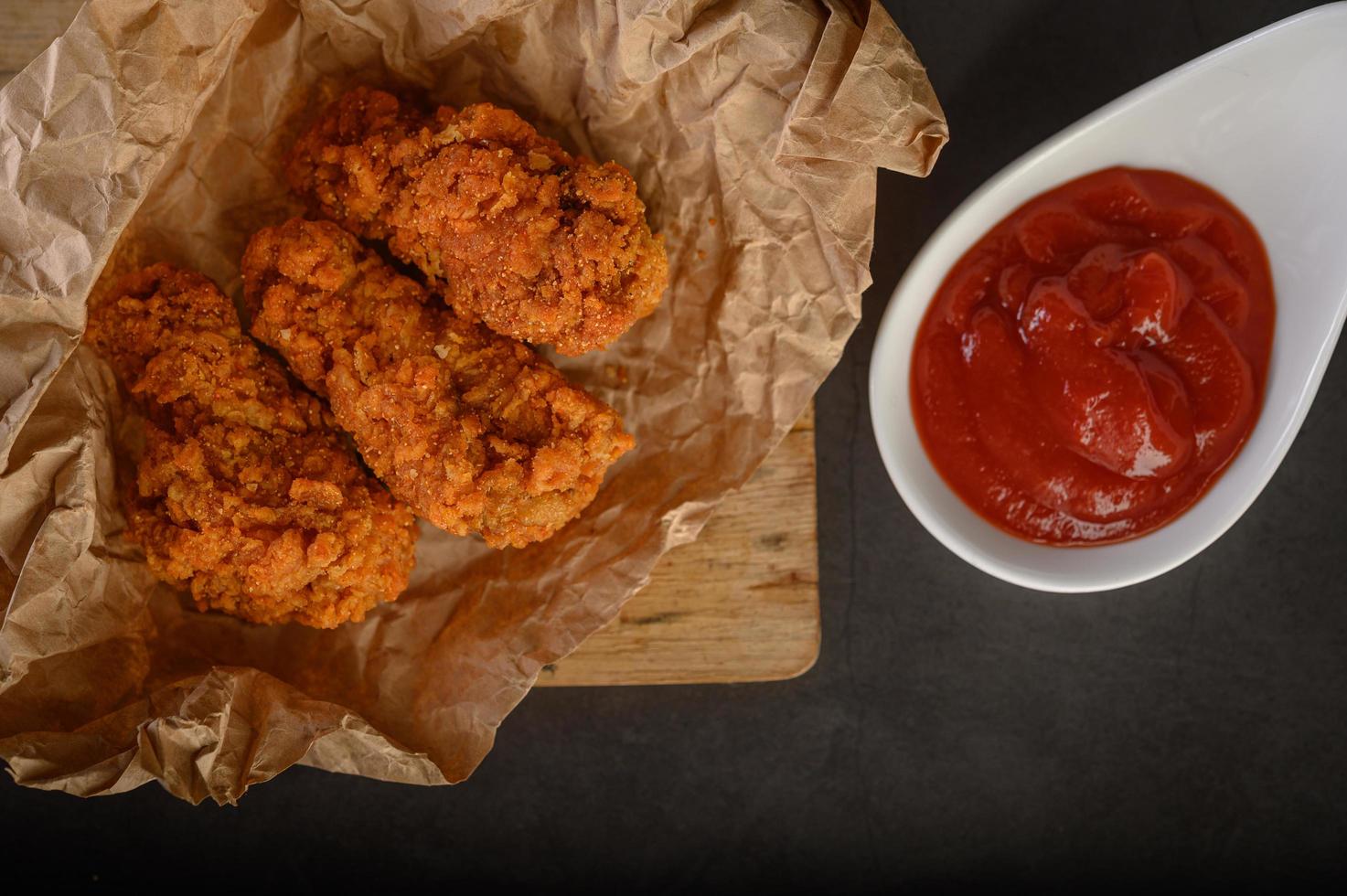 frango frito crocante em uma tábua com molho de tomate, vista de cima foto