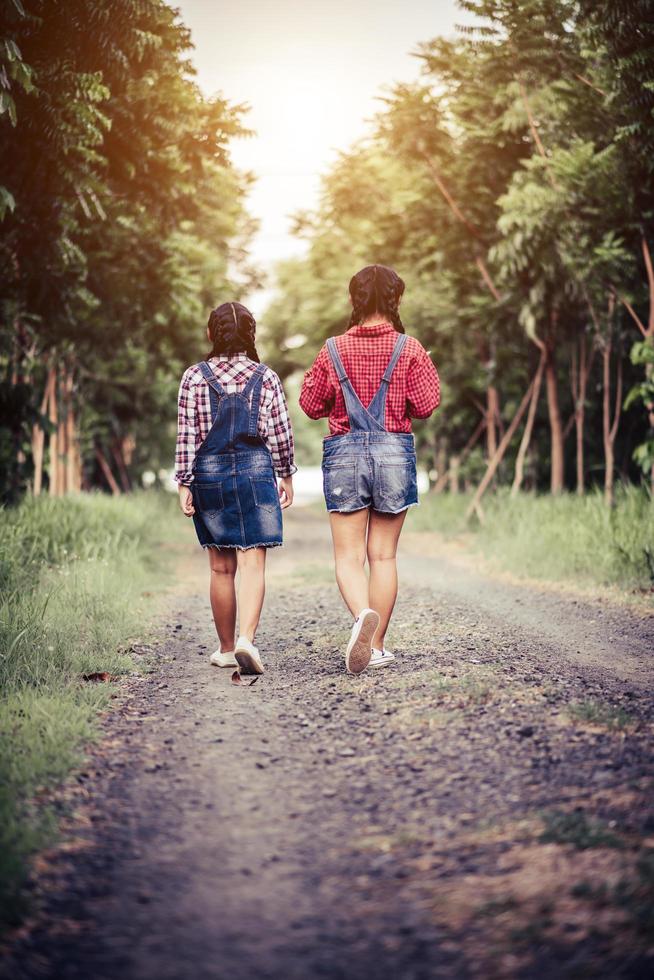 duas meninas caminhando ao longo de uma estrada na floresta na natureza foto