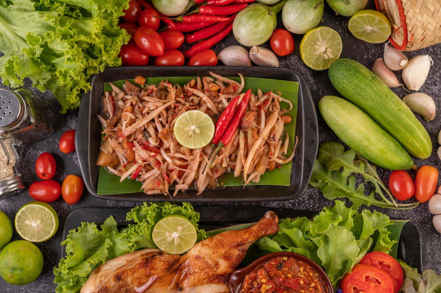 salada tailandesa de mamão rodeada de vegetais e frango foto