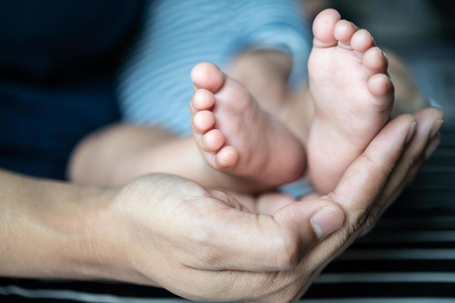 mãos de mães segurando pés de bebê foto