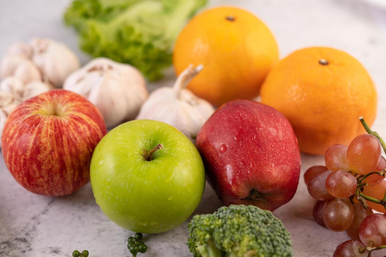 visão de close-up de maçãs, laranjas, brócolis, milho bebê, uvas e tomates foto
