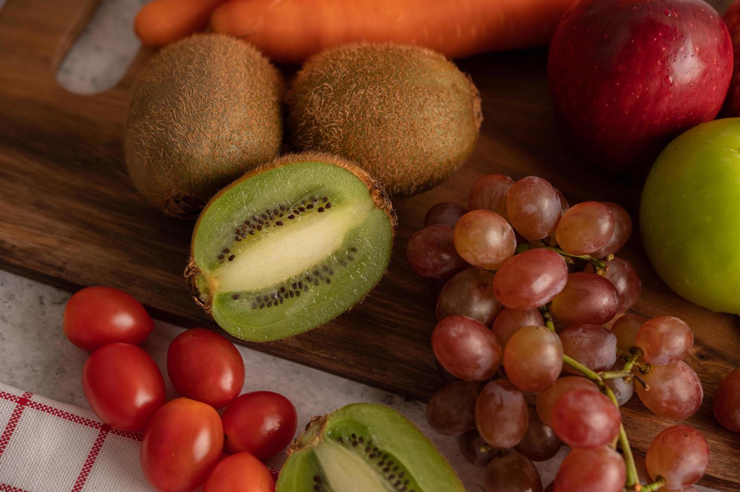 close-up de kiwi, uvas, maçãs, cenouras e tomates foto