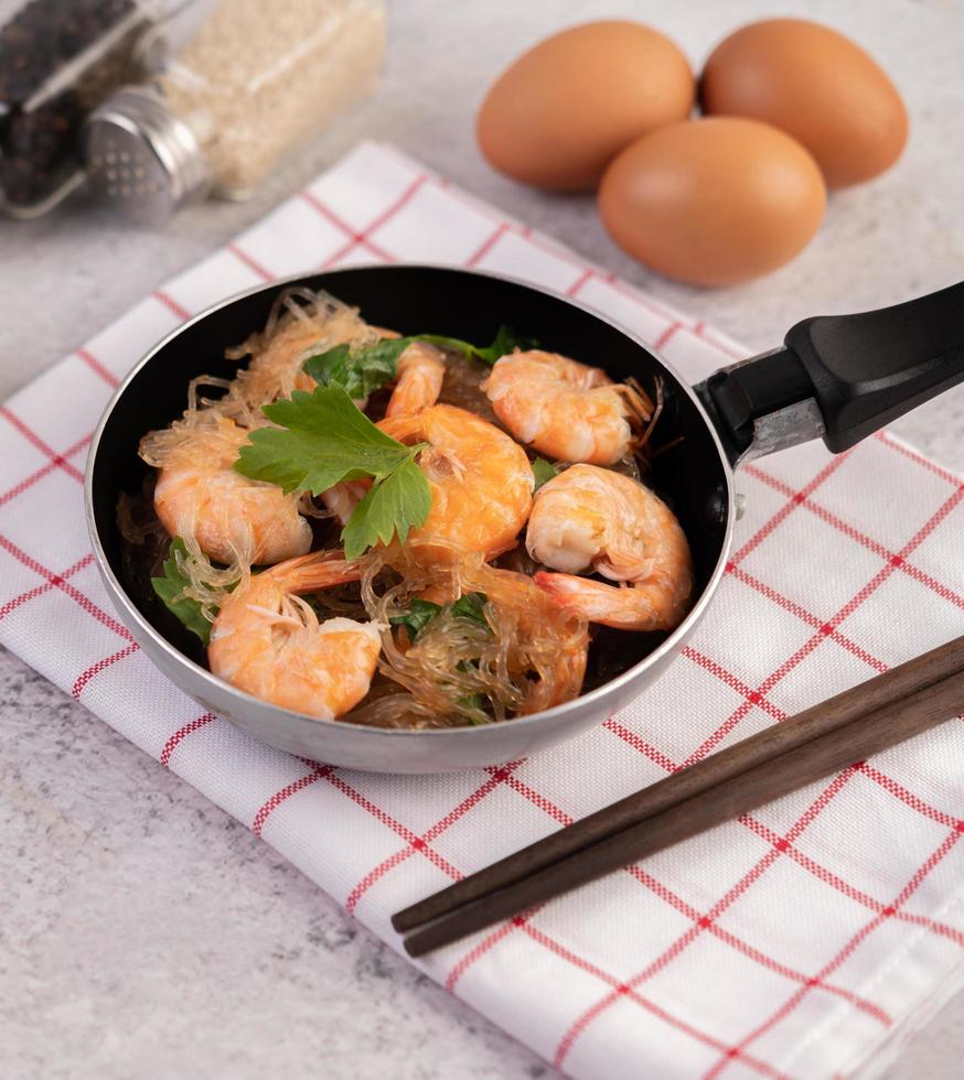 macarrão de vidro e camarão em uma frigideira foto