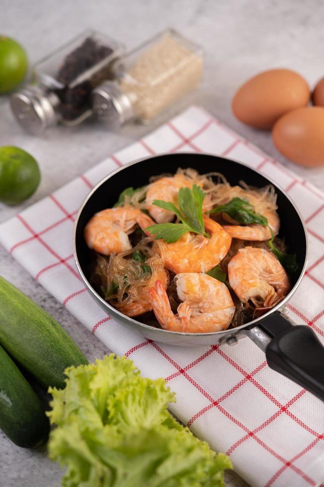 macarrão de vidro e camarão em uma frigideira foto