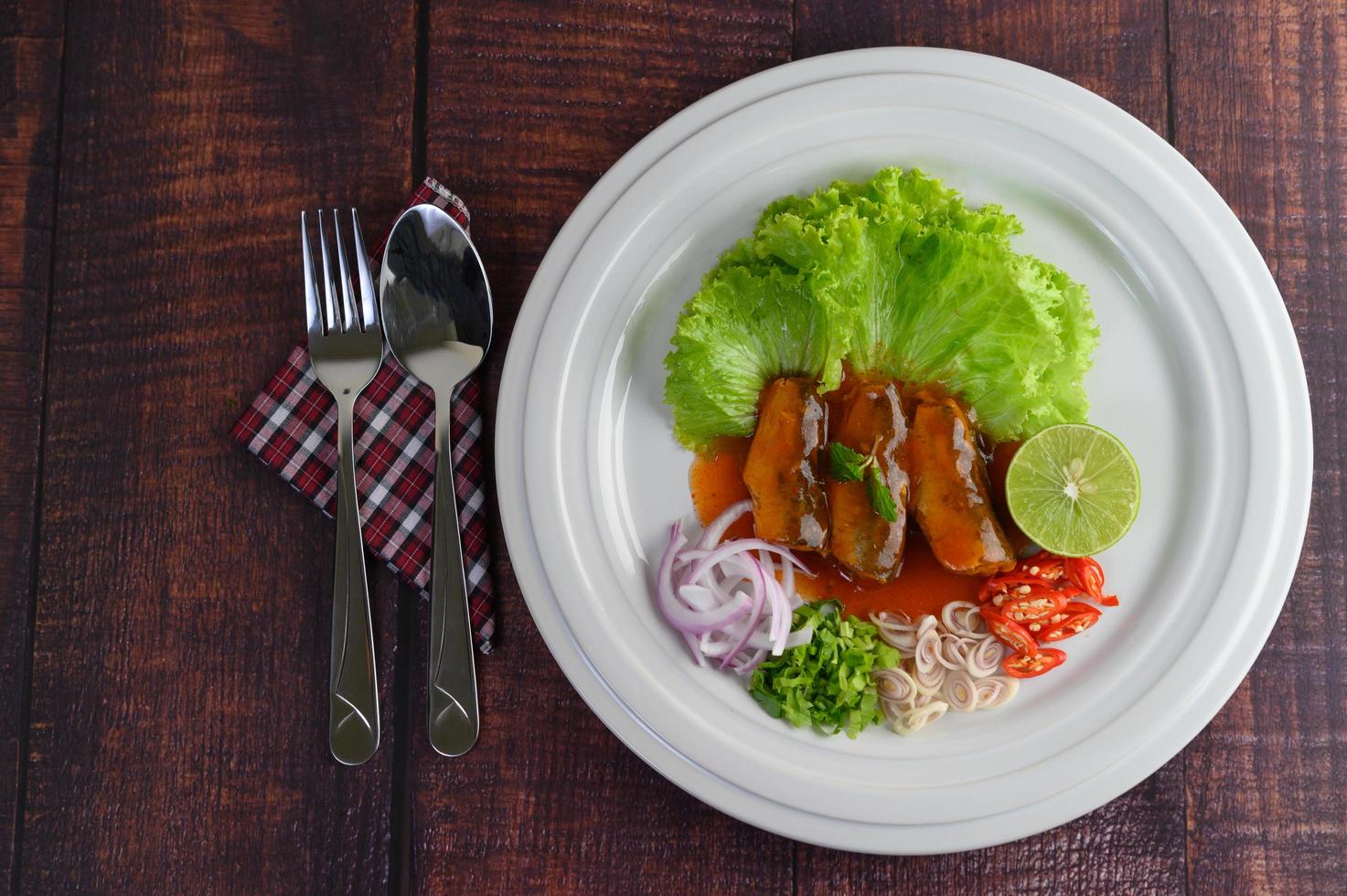 salada picante de sardinha com tomate em um prato branco foto