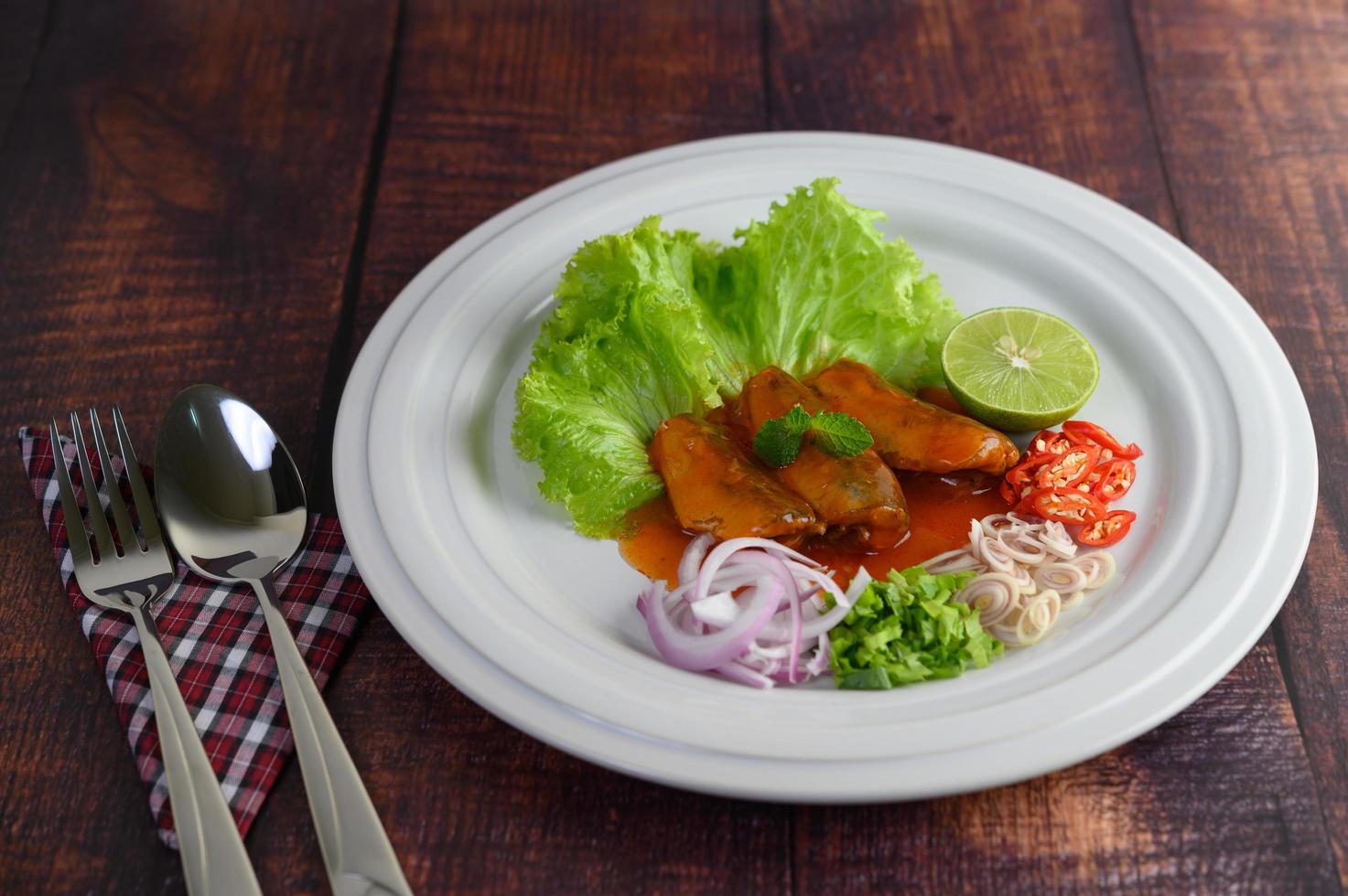 salada picante de sardinha com molho de tomate em prato branco foto