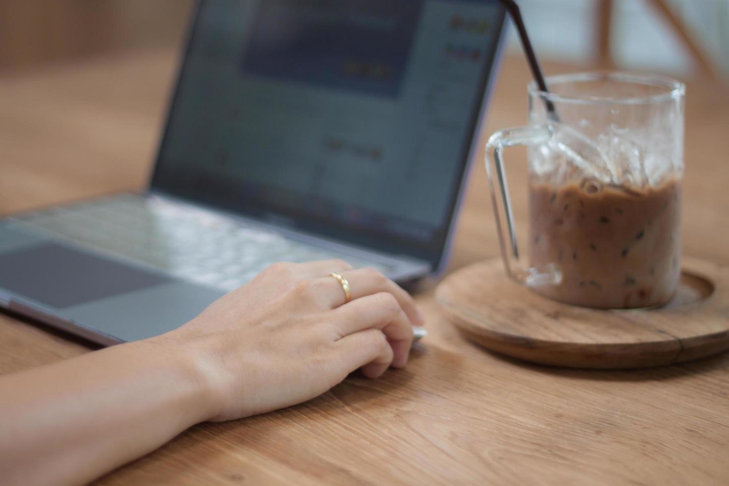 pessoa trabalhando em um laptop com um café gelado foto