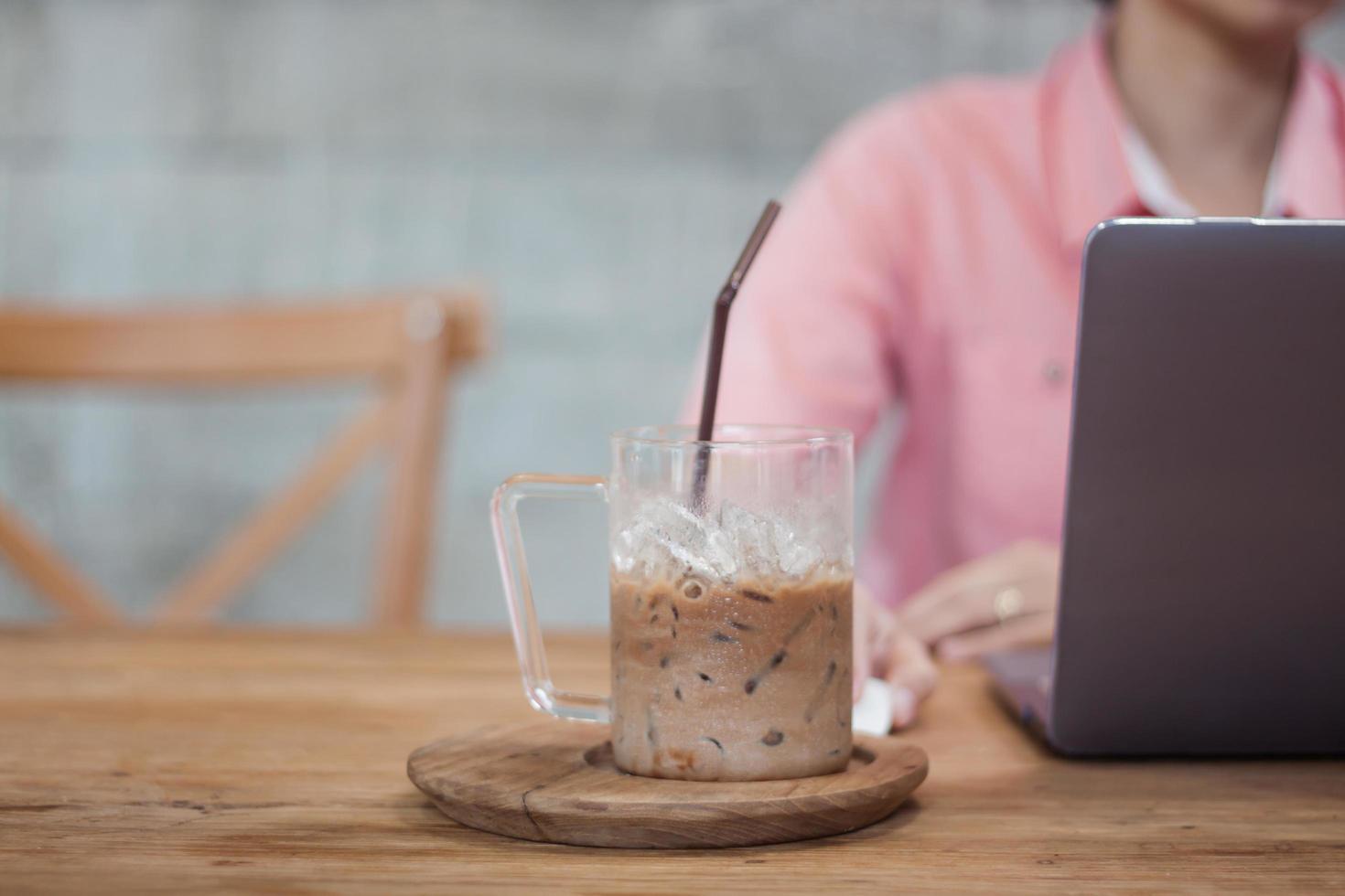 mulher trabalhando em um laptop em um café com um café gelado foto