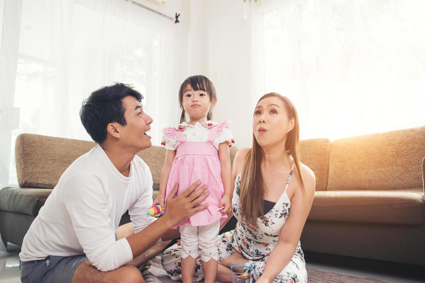 criança com os pais brincando no chão em casa foto