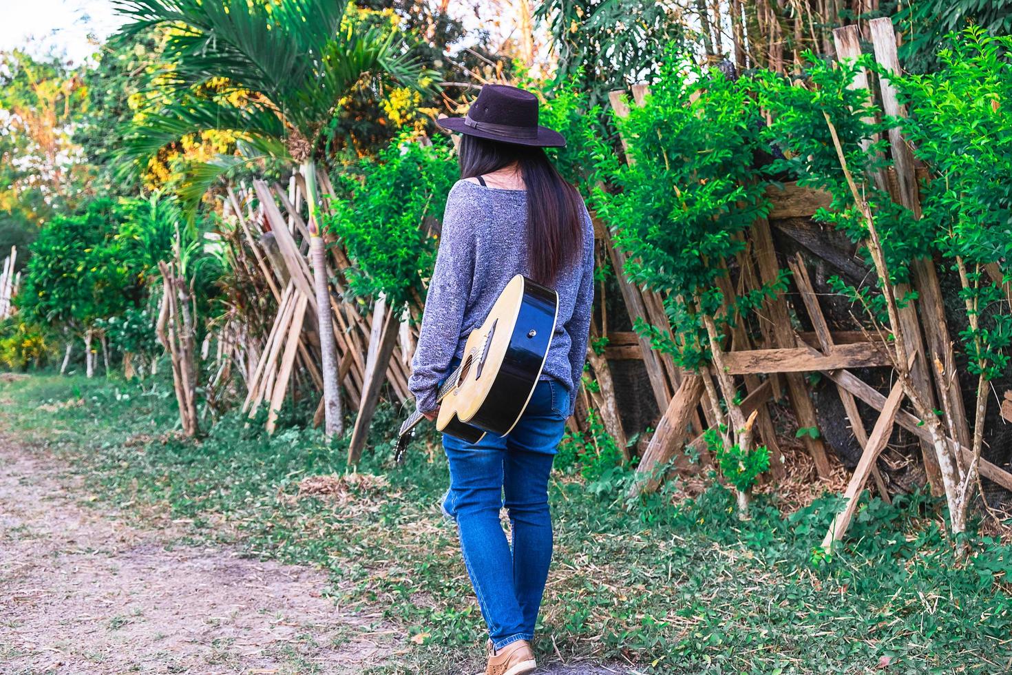 mulher caminhando em um jardim com um violão foto