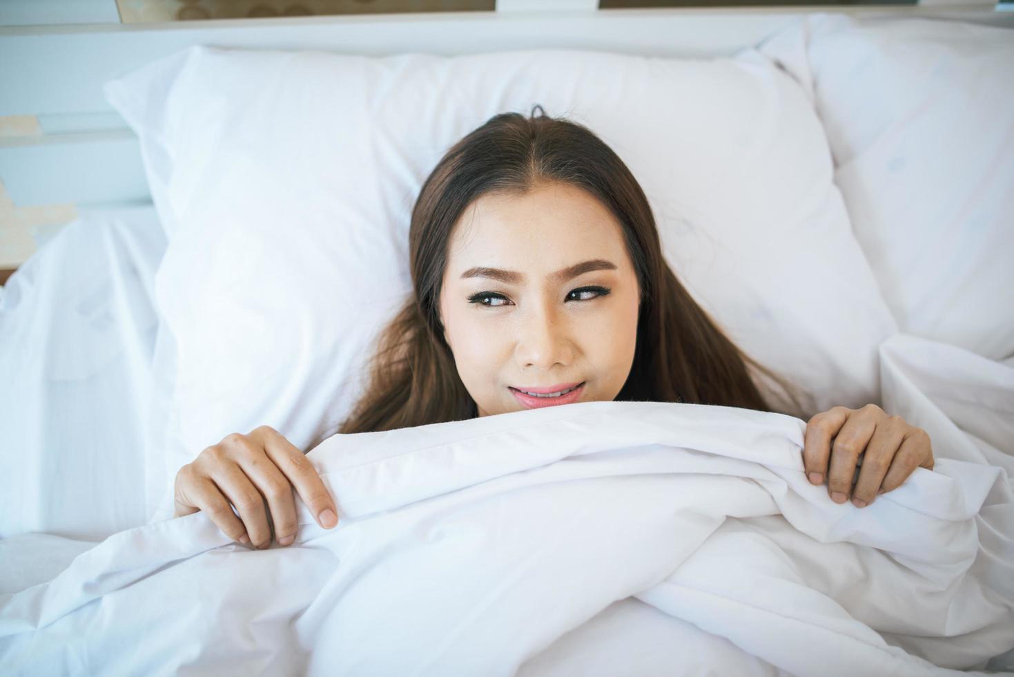 mulher acordando em sua cama, preguiçosa pela manhã foto