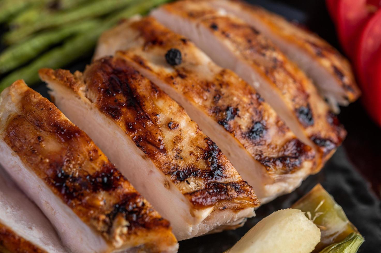 bife de frango com salada de legumes em um prato preto foto