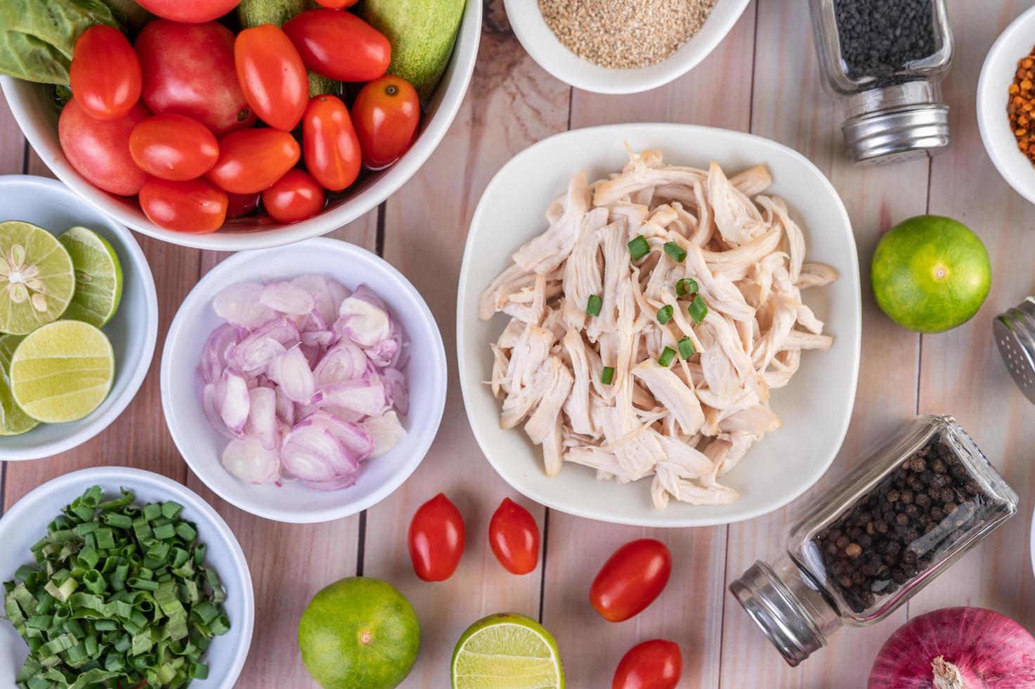 Pedaços de frango cozido com legumes e temperos em uma mesa de madeira foto