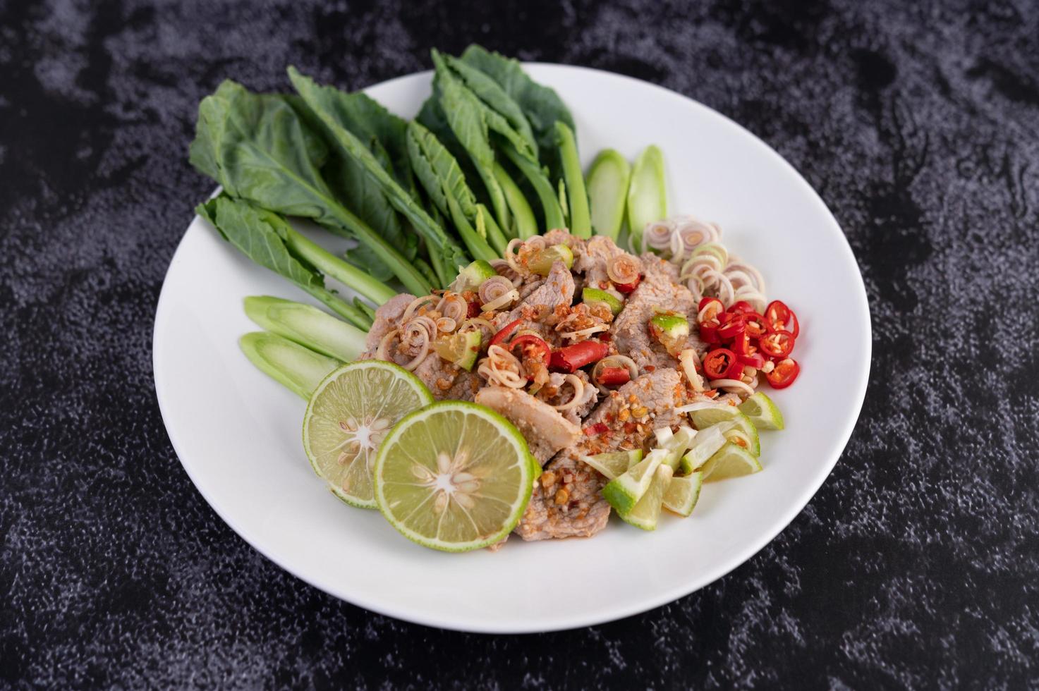 salada de porco com limão picante em uma cama de verdes foto