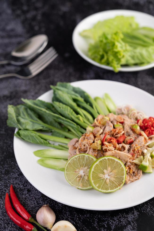 salada de porco com limão picante em uma cama de verdes foto